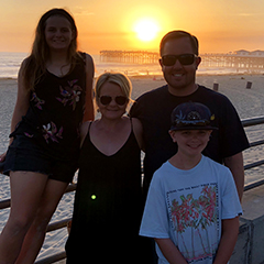 Brian Bailey with his wife and two children with a sunset in the background.